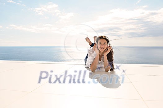 Young relaxed girl listening to the music on white headphones in modern home interior Young relaxed girl listening to the music on white headphones in modern home interior