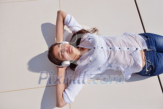 Young relaxed girl listening to the music on white headphones in modern home interior Young relaxed girl listening to the music on white headphones in modern home interior