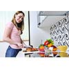 happy young  woman with apple in kitchen and other food and vegetables