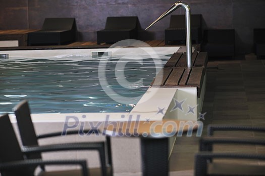 luxury indoor swimming  pool with wooden chair and bed
