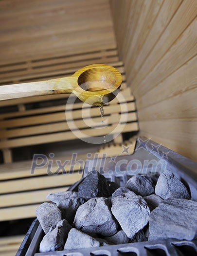 wooden luxury sauna indoor with hot stones and falling splashing water