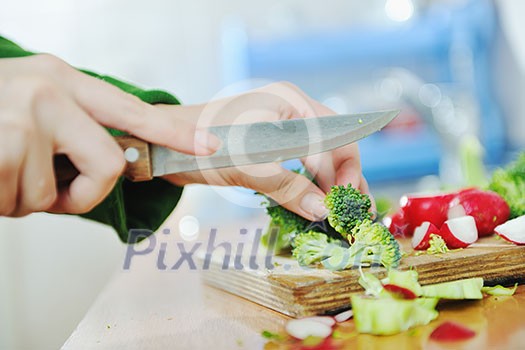 woman preparing healthy food salad with green and red vegetable and knife