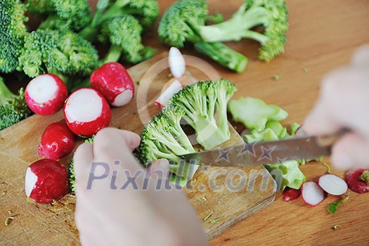 woman preparing healthy food salad with green and red vegetable and knife