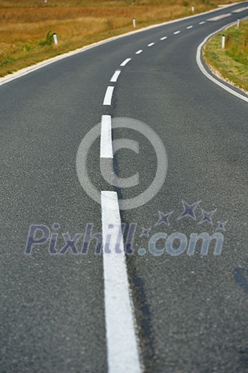 asphalt road through the green field and clouds on blue sky in summer day