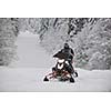 young man posing on snowmobile at beautiful winter day