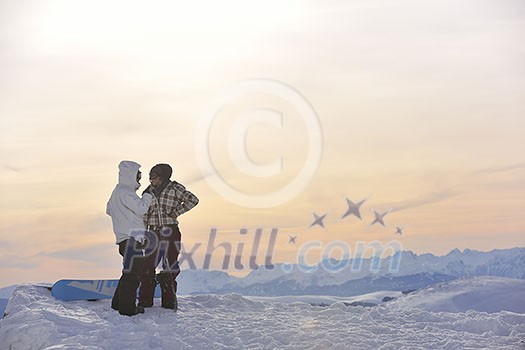 happy young snowboarder couple relax at top of mountain at beautiful sunny winter day