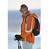 young skier relaxing in snow and looking mountain range at beautiful sunny winter day