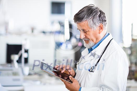 Senior doctor using his tablet computer at work (color toned image) Senior doctor using his tablet computer at work (color toned image)