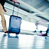 Airport rush: people with their suitcases walking along a corridor (motion blurred image; color toned image)