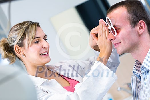Optometry concept - handsome young man having his eyes examined by an eye doctor
