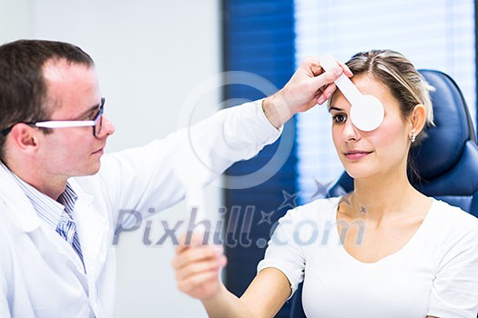 Optometry concept - pretty young woman having her eyes examined by an eye doctor