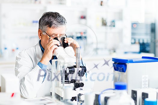 senior male researcher carrying out scientific research in a lab using a microscope (shallow DOF; color toned image) senior male researcher carrying out scientific research in a lab using a microscope (shallow DOF; color toned image)