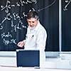 Senior chemistry professor writing on the board while having a chalk and blackboard lecture (shallow DOF; color toned image)