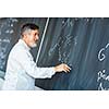 Senior chemistry professor writing on the board while having a chalk and blackboard lecture (shallow DOF; color toned image)