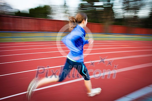 Young woman running at a track and field stadium Young woman running at a track and field stadium