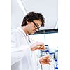 Young male researcher carrying out scientific research in a lab (shallow DOF; color toned image)