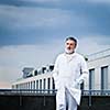 Renowned scientist/doctor standing on the roof of the research center/hospital looking confident (color toned image)