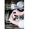 Housework: young woman putting dishes in the dishwasher