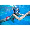 Underwater swimming: young woman swimming underwater in a pool, wearing a diving mask