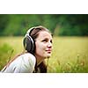 portrait of a pretty young woman listening to music on her mp3 player outdoors (daydreaming)