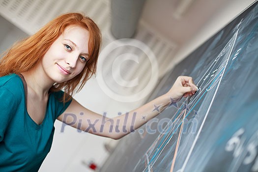 pretty young college student writing on the chalkboard/blackboard during a math class (color toned image; shallow DOF)