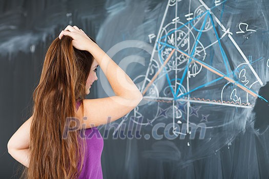 pretty young college student writing on the chalkboard/blackboard during a math class (color toned image; shallow DOF)