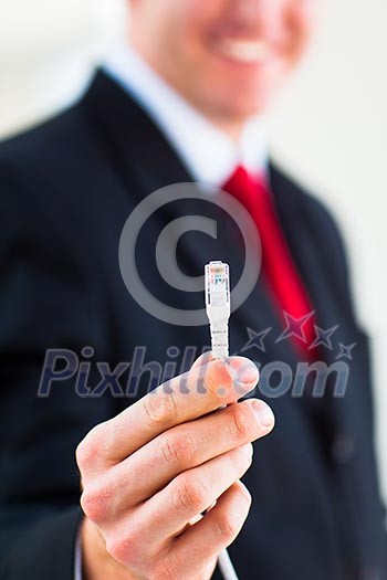 Young businessman holding an ethernet cable - stressing the importance of fast and reliable internet connection for a business (color toned image; shallow DOF)