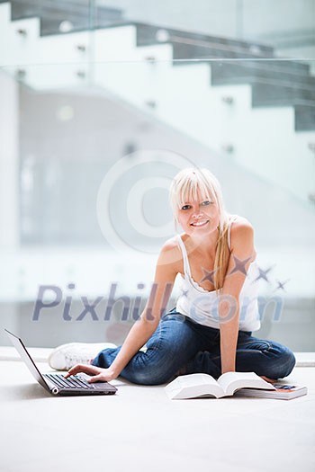 On campus - pretty female student with laptop and books working before class on her assignment/homework (color toned image) On campus - pretty female student with laptop and books working before class on her assignment/homework (color toned image)