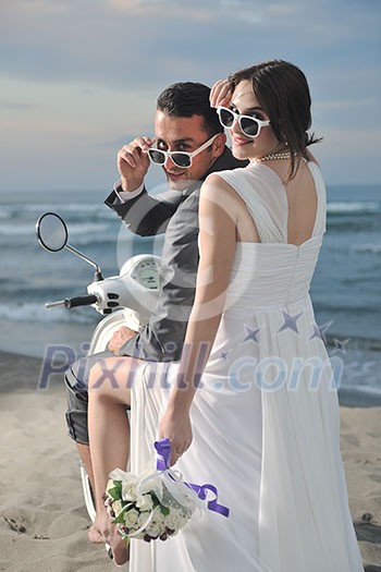 wedding sce of bride and groom just married couple on the beach ride white scooter and have fun