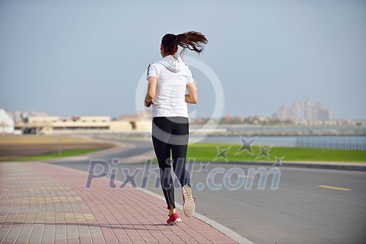 Running in city park. Woman runner outside jogging at morning with Dubai urban scene in background