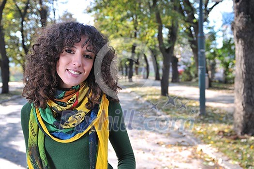 brunette Cute young woman with colorful scarf smiling outdoors in nature
