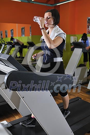 Young woman drinking water while working out in gym