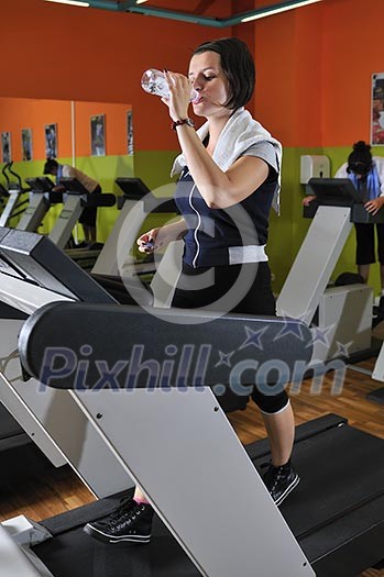 Young woman drinking water while working out in gym Young woman drinking water while working out in gym