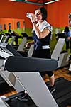 Young woman drinking water while working out in gym