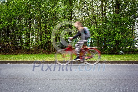 Motion blurred female biker on a city street, going fast