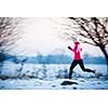 Winter running - Young woman running outdoors on a cold winter day (motion blurred image, color toned image)