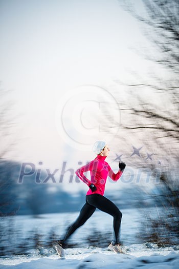 Winter running - Young woman running outdoors on a cold winter day (motion blurred image, color toned image)