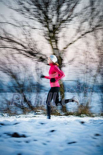 Winter running - Young woman running outdoors on a cold winter day (motion blurred image, color toned image)