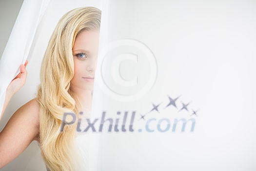 Gorgeous young woman/bride wearing a lovely dress, in a window, hiding in curtains(color toned image; shallow DOF)