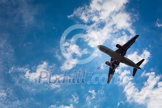 Dark silhouette of an airplane flying over the blue skies