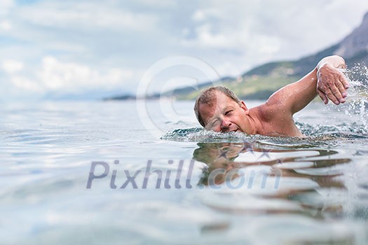 Senior man swimming in the Sea/Ocean - enjoying active retirement, having fun, taking care of himself, staying fit Senior man swimming in the Sea/Ocean - enjoying active retirement, having fun, taking care of himself, staying fit
