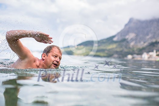Senior man swimming in the Sea/Ocean - enjoying active retirement, having fun, taking care of himself, staying fit Senior man swimming in the Sea/Ocean - enjoying active retirement, having fun, taking care of himself, staying fit
