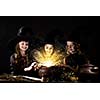 Three little Halloween witches reading spell above pot
