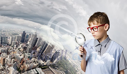 Cute school boy examining objects with magnifying glass