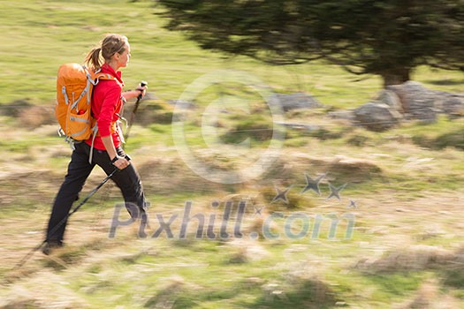 Pretty, young woman hiking in mountains (motion blurred image)