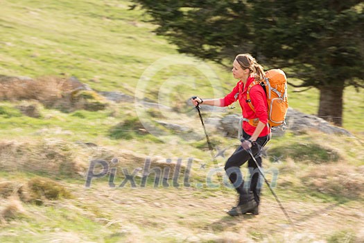 Pretty, young woman hiking in mountains (motion blurred image)