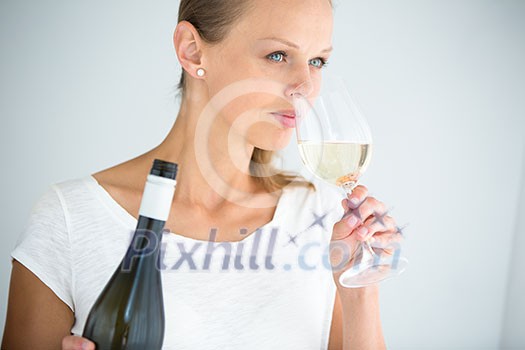 Gorgeous young woman with a glass of wine, smelling the lovely drink, savouring every sip (shallow DOF; color toned image)
