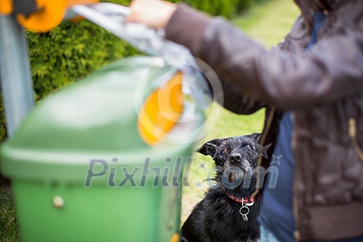 Do not let your dog foul! - Young woman grabbing a plastic bag in a park to tidy up after her dog later