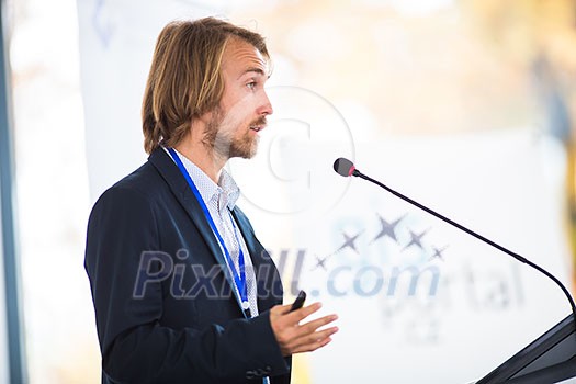 Handsome young man giving a speech at a conference