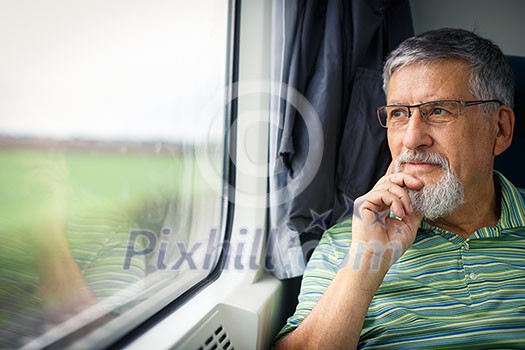 Senior man enjoying a train travel - leaving his car at home, he savours the time spent travelling, looks out of the window, has time to admire the landscape passing by